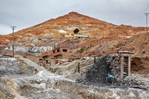 Small buildings on a mountainside with active mining operations and grey skies, The silver mines of
