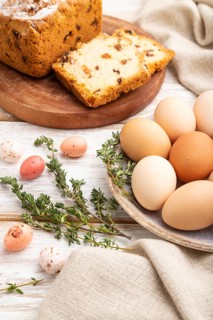 Homemade easter pie with raisins and eggs on plate on a white wooden background and linen textile.