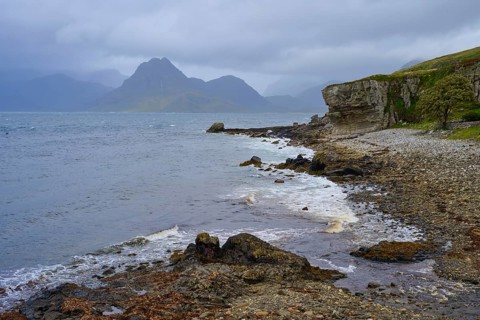 Rocky seaside coast with cloudy sky and mountain backdrop, Elgol Beach, Elgol, Isle of Skye,