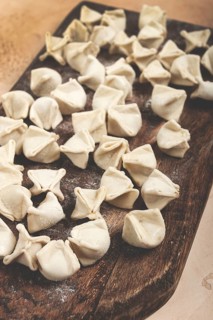 Traditional Turkish dumplings, raw, on a cutting board, top view, no people