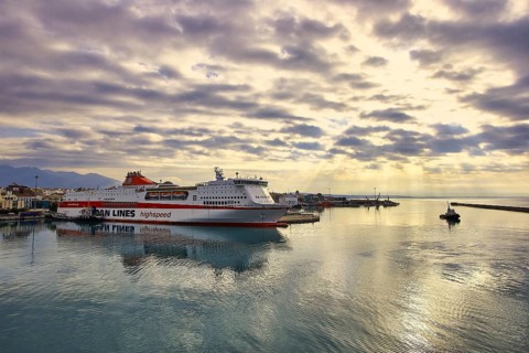 Ferry in port under a dramatic sky with sunbeams and calmly reflecting water, Old ferry port in