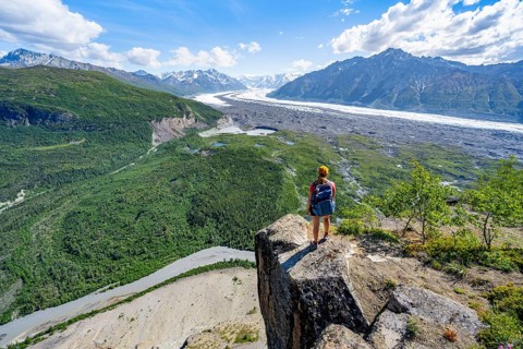 Young woman on a rocky outcrop enjoying the view, view of impressive mountain landscape with