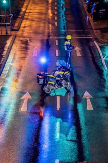 Policeman with motorbike, in rainy weather, blocking a road, police motorbike with blue light