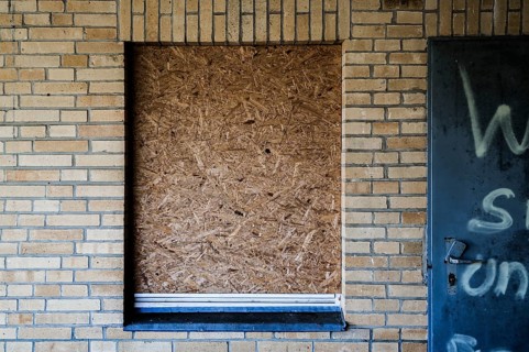Old building with brick walls and a window covered with OSB panels