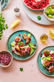Delicious meatballs served with fresh cucumbers, pickled onions, yogurt, pomegranate seeds, and