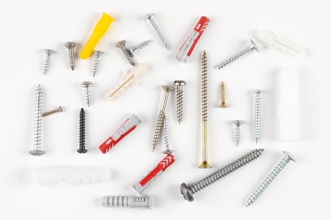 Various screws and plugs scattered on a white surface