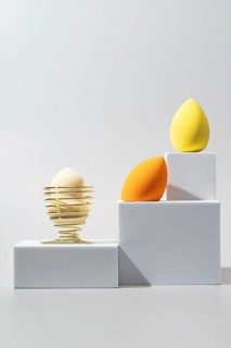A striking arrangement of cosmetic sponges in yellow and orange hues, showcased on minimalist white