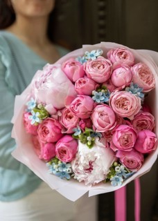 A woman holding a beautifully arranged bouquet of fresh pink and white flowers with touches of