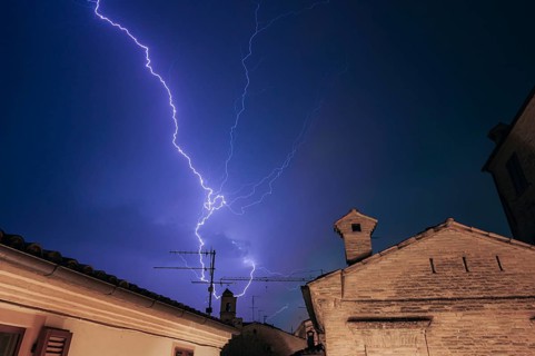 Majestic lightning bolts illuminate the night sky overTreia, Italy. The vibrant energy of the storm