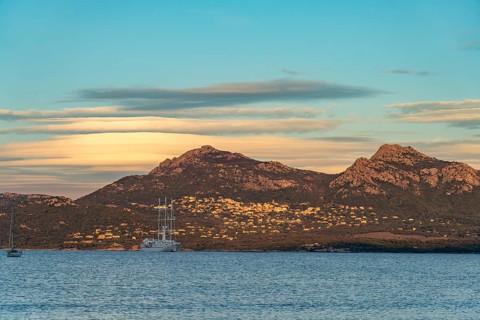 View of Lumio, sailing cruise ship Wind Spirit and the mountains at Calvi Bay, Balagne, Corsica,