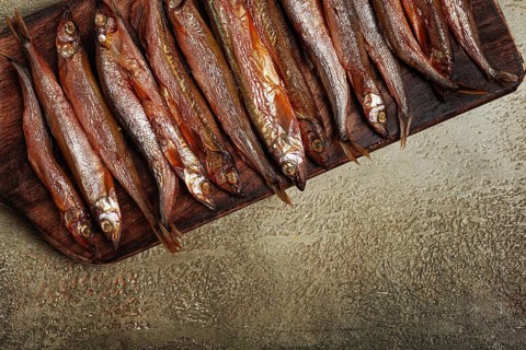 Cold smoked capelin, on a wooden chopping board, no people