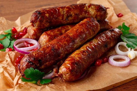 Fried kupaty on parchment, with red onion and pomegranate, kupaty, Georgian cuisine
