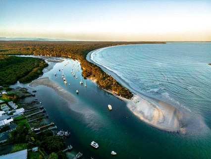 A stunning aerial view captures a serene coastal landscape with a curving coastline, calm river,