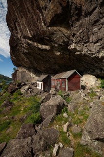 Historical wooden houses sheltered under a massive rock overhang. Summer, Helleren (Helleren),