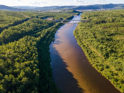 A serene view of a winding river surrounded by lush greenery in Vladivostok, Russia. The scene