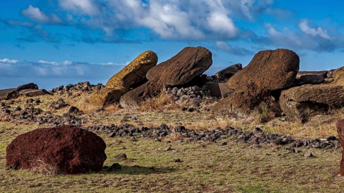 Three fallen moai lie side by side under a cloudy sky on Easter Island, the moai statues on Easter