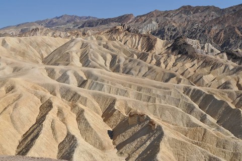 Hills shaped by erosion in a vast desert landscape under blue skies, Zabriskie Point, Death Valley