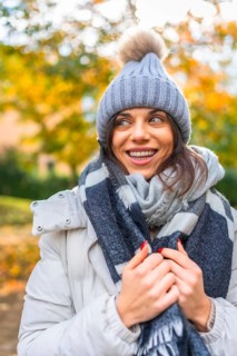 Vertical photo of a caucasian cute beauty woman with warm clothes in a park during autumn