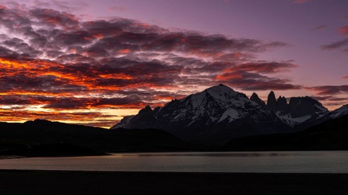 Torres del Paine massif with snow-capped peaks at sunset, red clouds over Laguna Amarga, Torres del