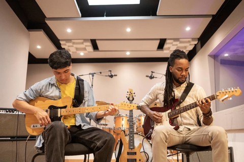 Two musicians engage in a creative jam session, playing electric guitars in a contemporary
