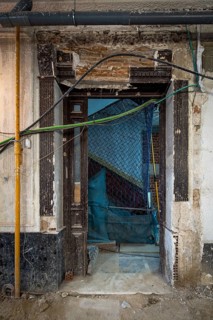 A historic building entrance under renovation, showing exposed bricks, wires, and scaffolding. A