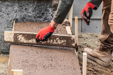 Construction Worker Leveling Wet Cement Into Wood Framing