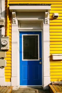 A striking bright blue door set against a vivid yellow wooden facade of a house in St. John's,