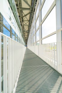Long, light-flooded corridor with metal floor and glass windows, Motorworld Böblingen, Germany
