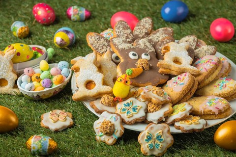 Decorated Easter cookies on a plate with colorful eggs in the grass