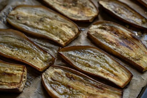 Close-up view of oven roasted eggplant slices, showcasing their rich texture and golden-brown