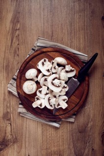 Fresh mushrooms, chopped, in a wooden bowl, whole, top view, no people