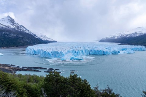 Perito Moreno glacier with calving event, rising ice block and wave rings in the water of Lake