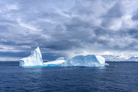 Iceberg with prominent tip and tabular section floating in the Southern Ocean, snow-covered