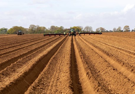 John Deere 6R tractor with wide-boom conveyor system planting platform for potatoes, Shottisham,
