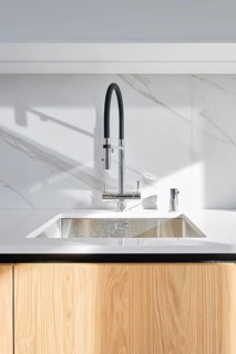 A contemporary kitchen showcases a stylish sink with a stainless steel basin and an elegant black