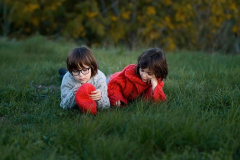 A young boy and girl, siblings, enjoy a leisure day in a grassy park surrounded by autumn colors.