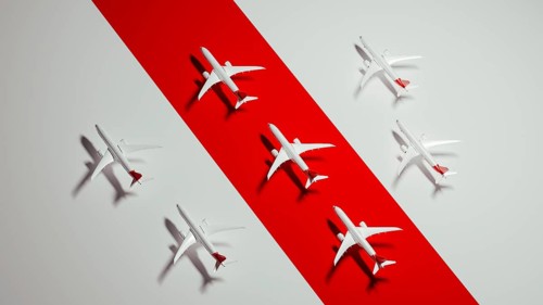 Miniature airplane models are displayed on a striking red surface, highlighting the concept of air