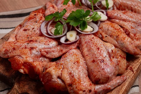 Chicken wings, marinated and laid out on a wooden platter, ready for cooking, grilling or baking,