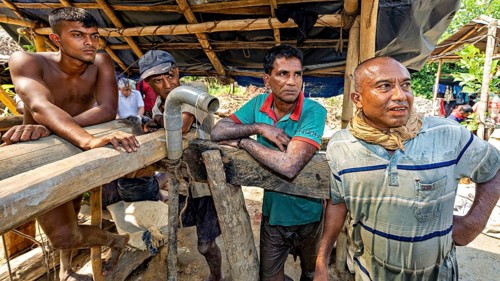 Four men work together on a wooden structure in an open area, the sapphire and gemstone mines at