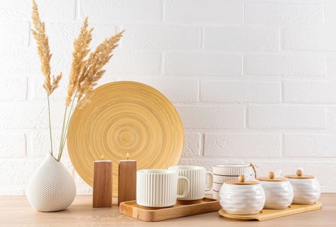 A modern kitchen table is adorned with minimalist tableware, including ceramic mugs, wooden dish,
