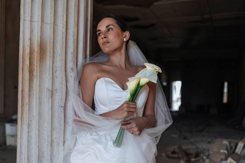 A bride in a stunning white dress poses with calla lilies at an ancient villa in Treia, Italy. The