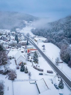 Snow-covered village with church and main street, surrounded by forests, Enzklösterle, Calw