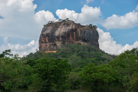 Sigiriya Rock, an ancient fortress in Sri Lanka, rises majestically amidst lush greenery under a
