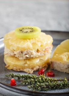 Pieces of baked pork with pineapple, cheese and kiwi on gray plate, side view, close up, selective
