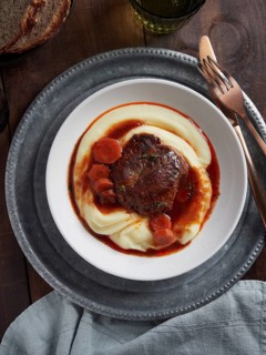 Dish with braised pork cheeks with carrots and gravy over mashed potatoes. Spanish cuisine. View