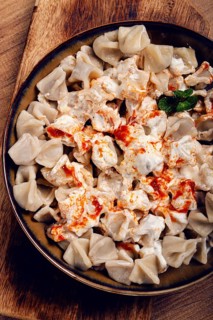 The dish features a generous serving of Turkish dumplings topped with velvety yogurt and a drizzle