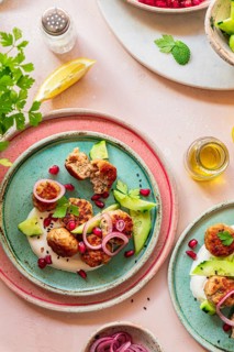 A vibrant Mediterranean meatballs dish on colorful plates, garnished with cucumber, onion, yogurt