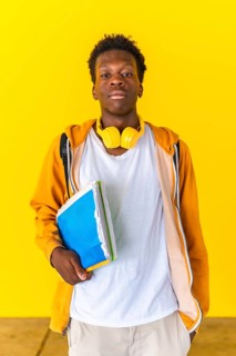 Studio portrait with yellow background of an african student standing serious