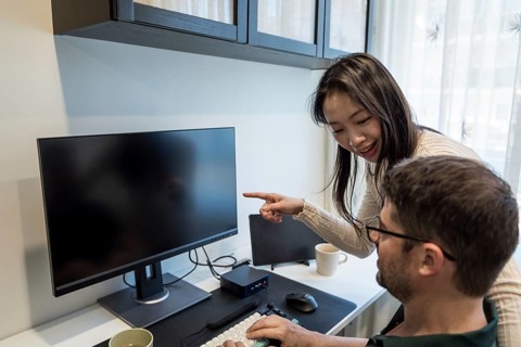 A diverse couple is seen engaging in a collaborative project at home, with the woman pointing to
