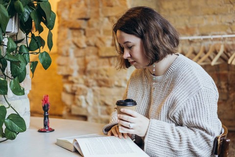 A young woman enjoys reading a book in a cozy bookstore, surrounded by a warm atmosphere She holds